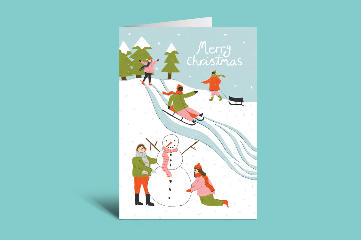 Christmas card with people building a snowman on a green background