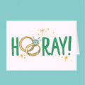 Card with 'Hooray!' text and wedding rings on a teal background