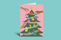 Colorful Christmas tree card with various ornaments on a pink background