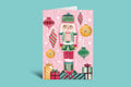 Christmas-themed greeting card with a nutcracker design on a pink background
