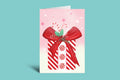 Greeting card with a red bow and candy canes on a pink background