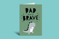Card with dinosaur illustration and text 'Dad you're so brave' on a green background