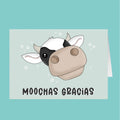 Cartoon cow face with 'MOOCHAS GRACIAS' text on a light blue background