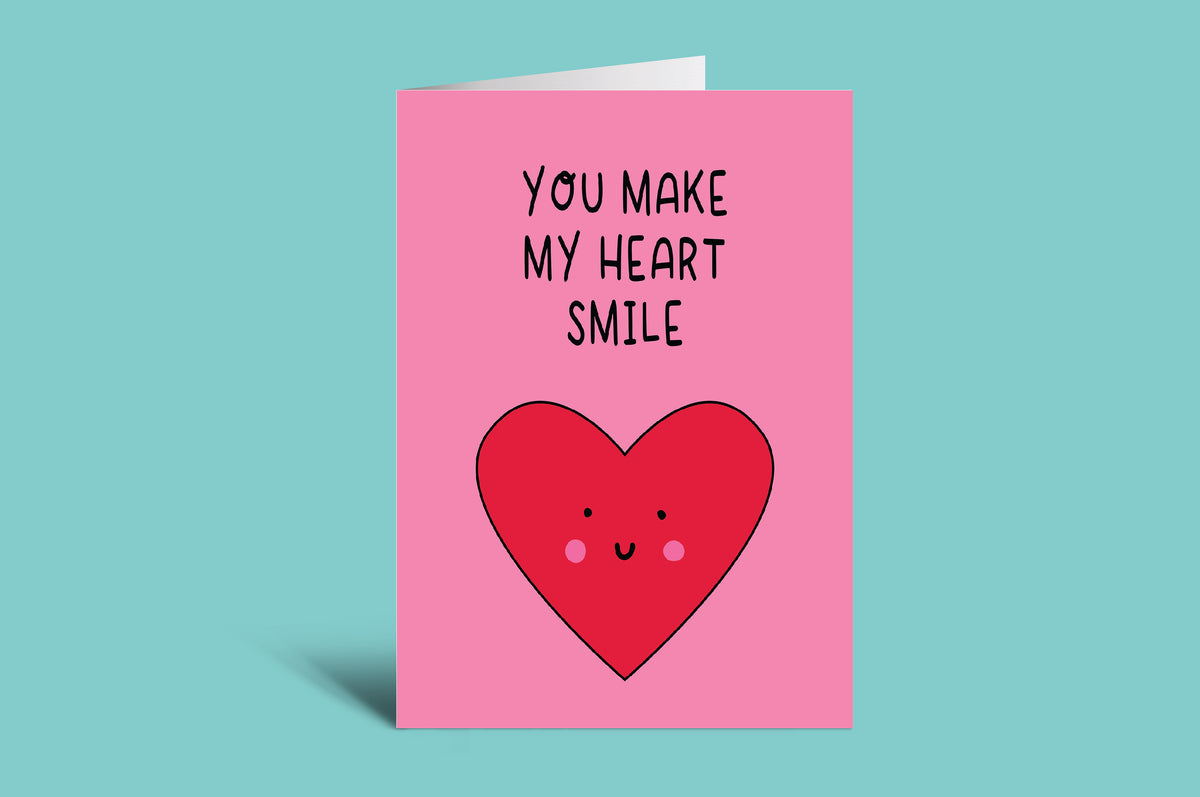 Card with a red heart and text 'You make my heart smile' on a pink background