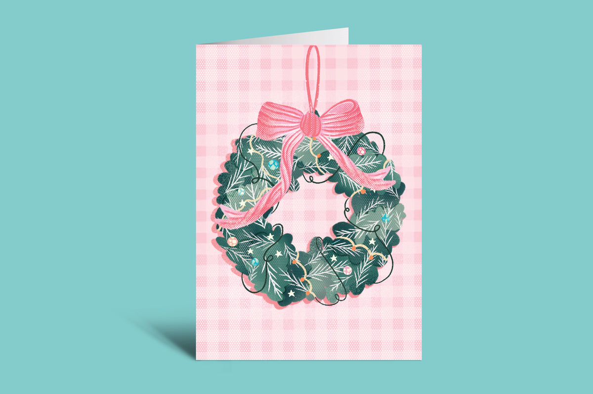 Greeting card with a wreath and pink bow on a pink checkered background