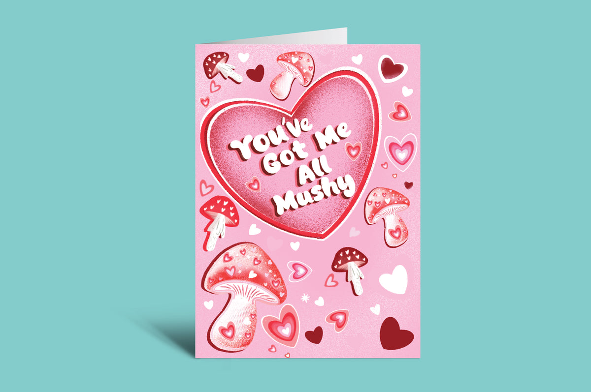 Pink greeting card with heart design and mushroom illustrations on a teal background