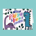Card with cartoon dinosaurs and text 'Rawr-some & Dino-mite Grandparents' on a light blue background