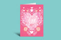 Pink card with heart and floral design on a green background