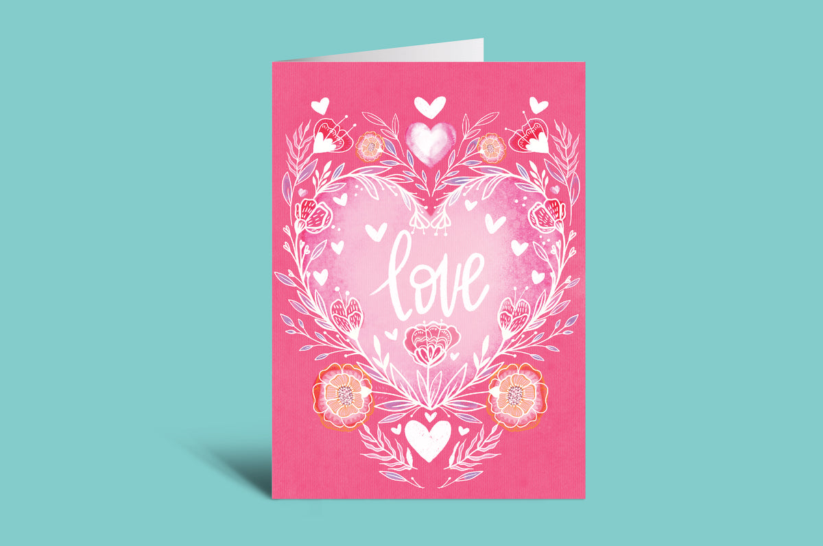 Pink card with heart and floral design on a green background