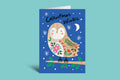 Christmas card with a penguin holding a floral branch on a blue background