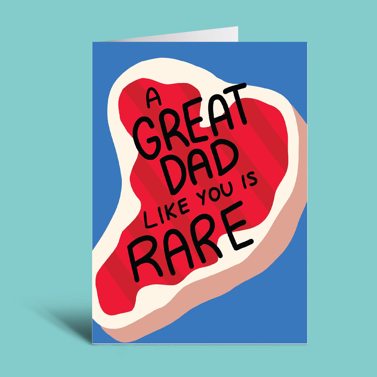 A folded greeting card shown standing upright on a light aqua background. The card features a stylized red steak graphic with cream and tan edges and the text 'A GREAT DAD LIKE YOU IS RARE' in black lettering.