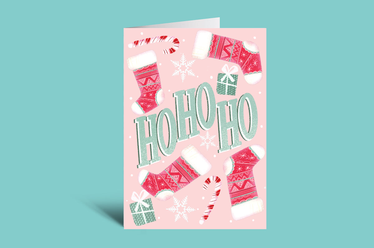 Pink Christmas card with 'HO HO HO' text and festive illustrations on a teal background