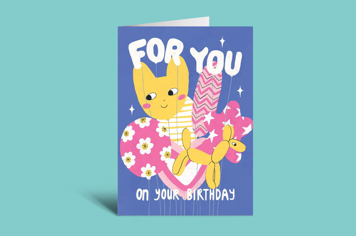 Birthday card with a cartoon character holding a balloon dog on a teal background