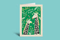 Greeting card with two giraffes on a green background