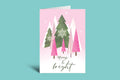 Christmas card with trees and 'Merry & Bright' text on a pink background
