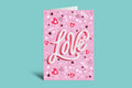 Pink card with 'Love' text and heart designs on a green background