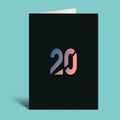 A black greeting card standing upright on a light aqua background, featuring a stylized '20' in a blue-to-pink gradient on the front.