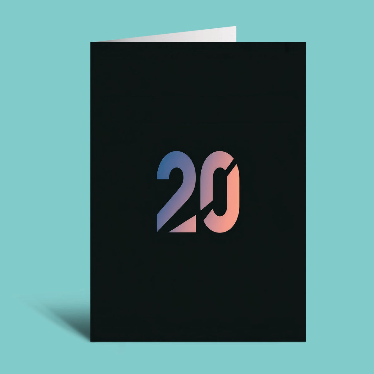 A black greeting card standing upright on a light aqua background, featuring a stylized '20' in a blue-to-pink gradient on the front.