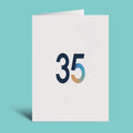 A white greeting card standing upright on a light aqua background, featuring the number 35 in dark navy with a blue-to-gold gradient on the 5.