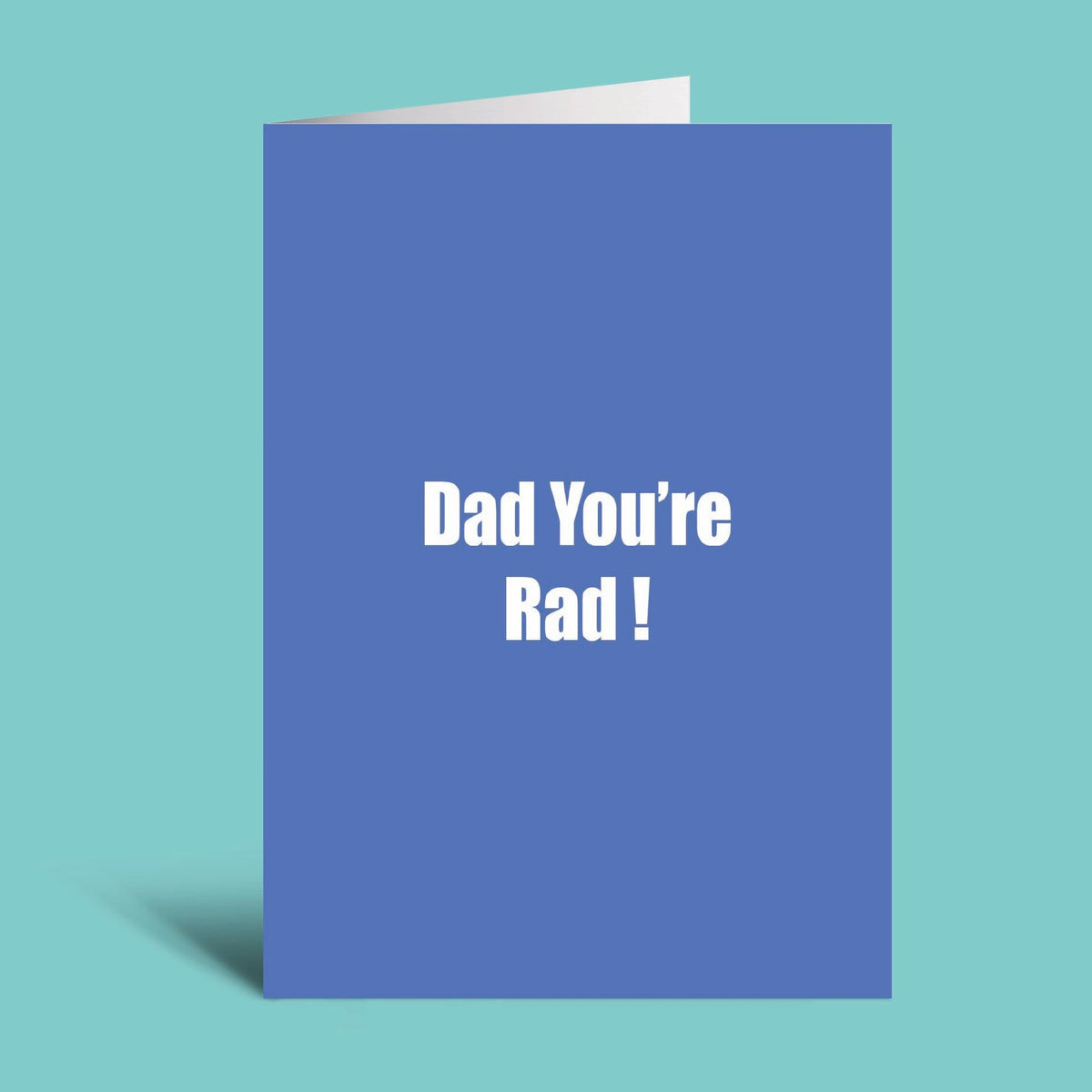 A blue greeting card with the text 'Dad You're Rad!' in white, shown standing upright against a light teal background.