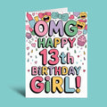 A white greeting card with colorful retro-style text reading 'OMG HAPPY 13th BIRTHDAY GIRL!' surrounded by playful doodles like cupcakes, lipstick, bows, hearts, and emoji faces, shown on a light aqua background.