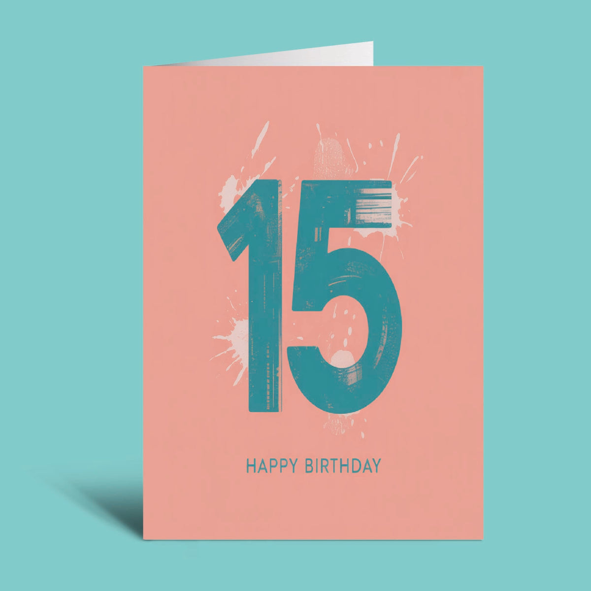 A coral pink 15th birthday greeting card with a teal '15' and white paint splatters, with 'HAPPY BIRTHDAY' printed below, shown on a solid teal background.