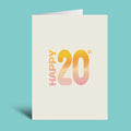 A cream-colored greeting card standing upright against a solid turquoise background. The card features the text 'HAPPY 20th' in a vertical, modern font with a warm yellow-to-pink gradient fill.