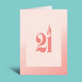 A minimalist greeting card or art print with a pale pink background, featuring the number 21 stylized in coral-red with a flame motif, shown standing against a solid turquoise background.