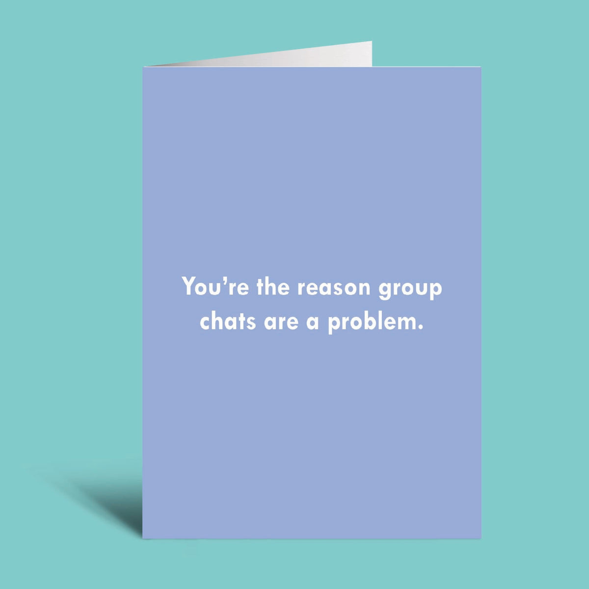 A folded greeting card with a light lavender-blue cover and white text reading 'You're the reason group chats are a problem.' shown on a solid aqua background.