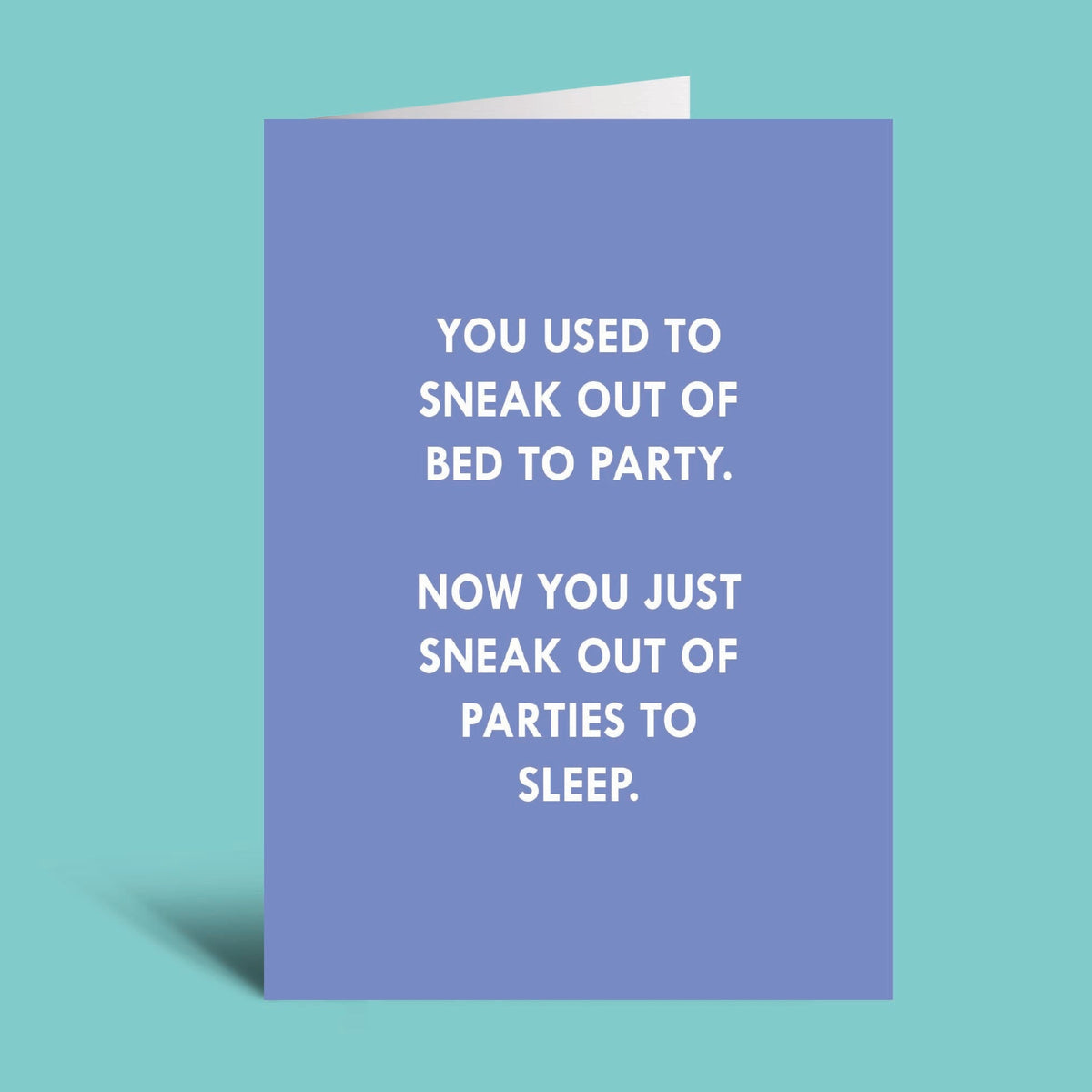 A folded greeting card with a lavender-blue front and white printed text, shown standing against a solid aqua background. The card reads: 'YOU USED TO SNEAK OUT OF BED TO PARTY.