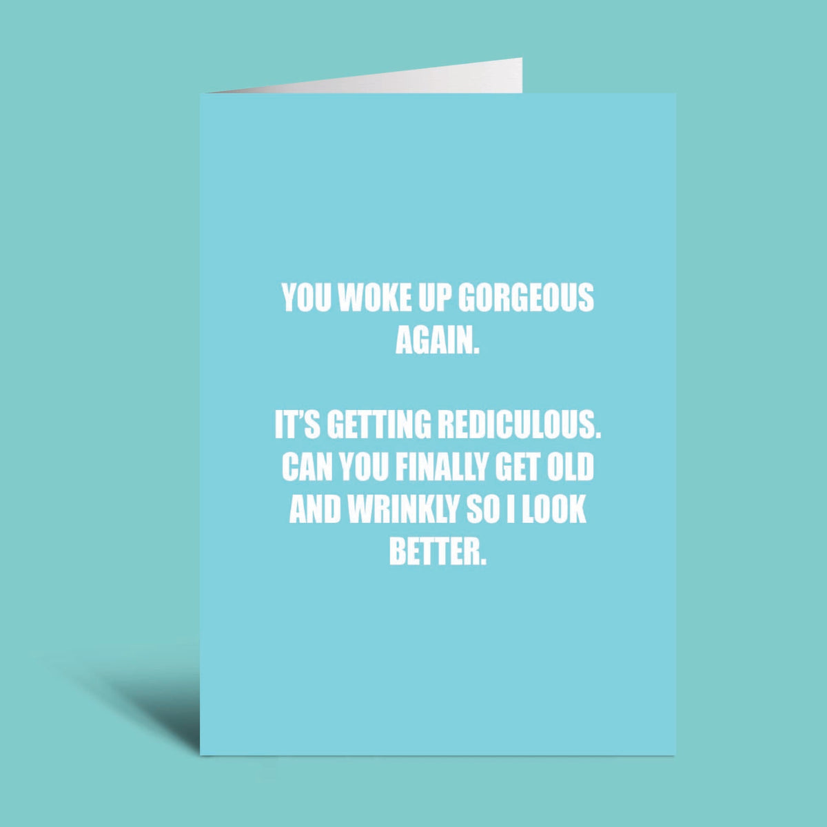 A light blue greeting card with white text that reads, 'YOU WOKE UP GORGEOUS AGAIN. IT'S GETTING REDICULOUS.