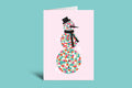 Greeting card with a colorful snowman design on a pink background