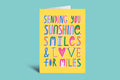 Colorful card with text 'Sending you sunshine, smiles & love for miles' on a green background