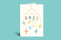 Greeting card with colorful baby mobile design and 'BABY' text on a green background