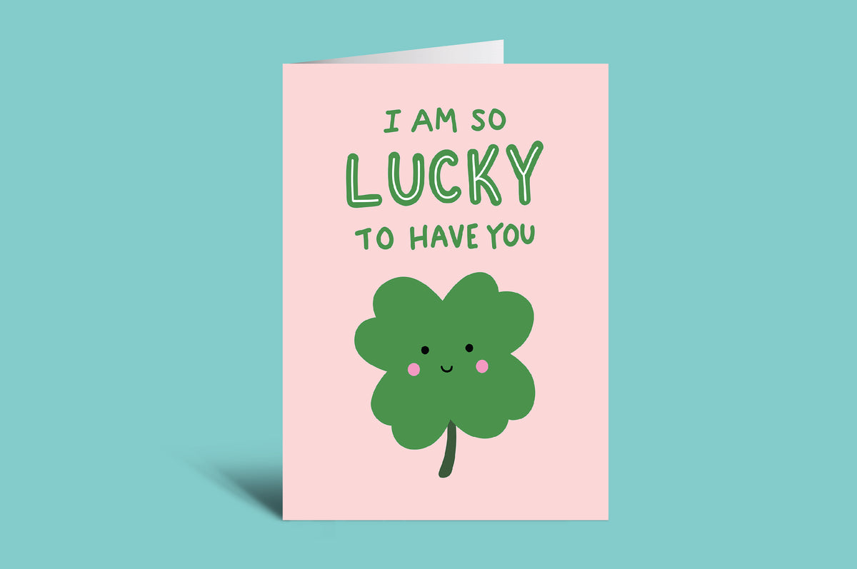 Greeting card with a green four-leaf clover and text on a pink background