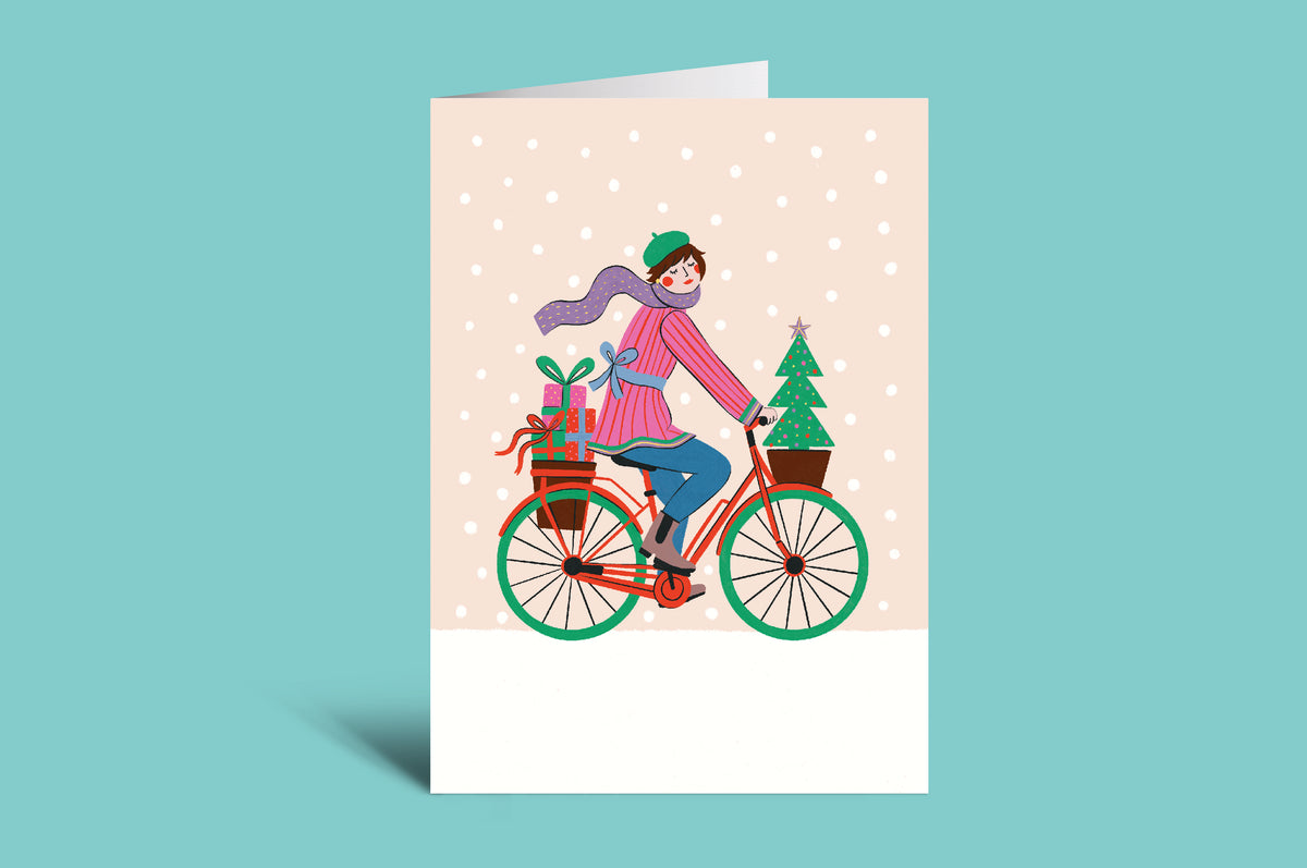 Greeting card with a cyclist and Christmas tree design on a pink background