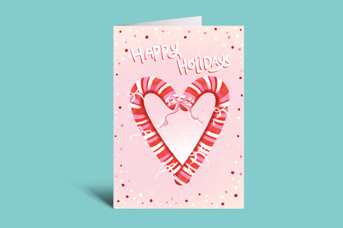 Greeting card with candy canes forming a heart and 'Happy Holidays' text on a pink background.